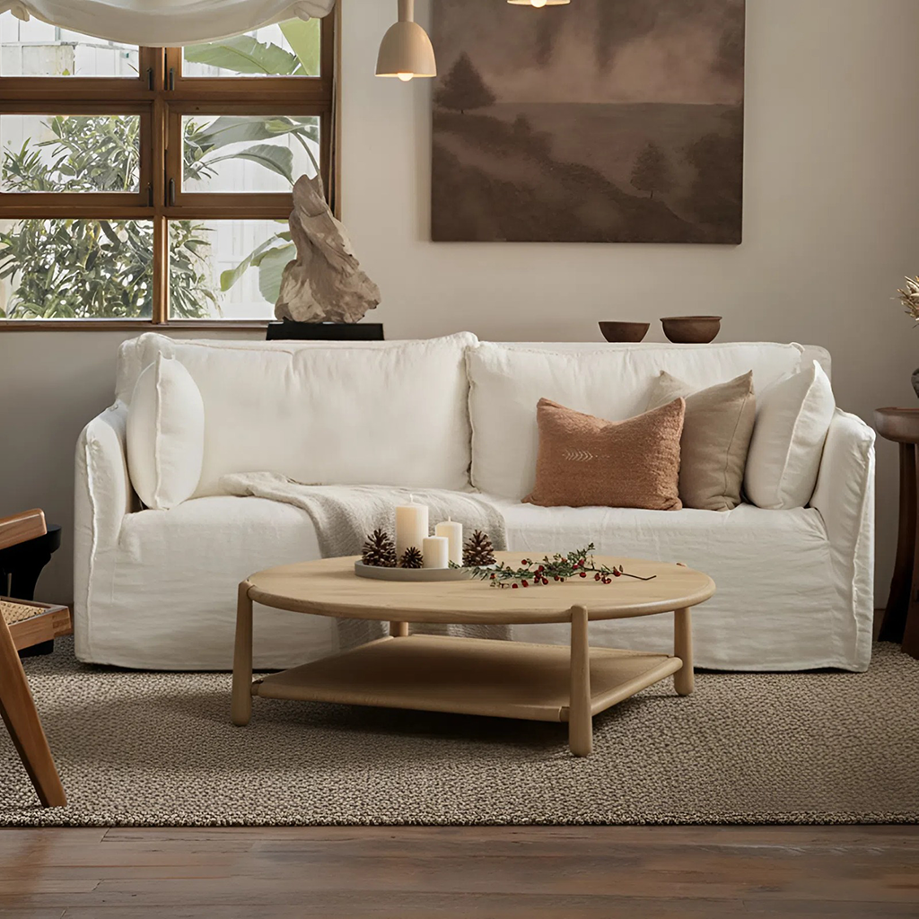 Farmhouse round wooden coffee table with lower shelf side angle view with sofa