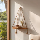 Floating wooden hanging shelf with braided rope displaying decor near window