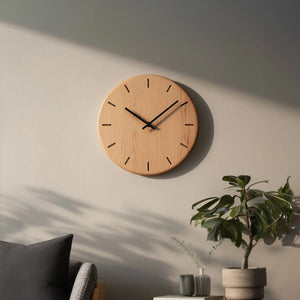 Minimal round wooden wall clock with linear hour marks mounted above sofa 