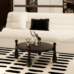Modern round wooden coffee table with sculptural legs side view in styled space